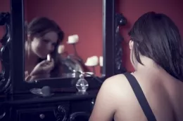 Kat Dee at More Than Nylons | As pretty as a picture, here you can see Kat putting the finishing touches to her makeup. But with a mere whisper in her ear, she's easily convinced that her dress – whilst gorgeous – detracts from the look. Those holdups can definitely stay though………….for now.