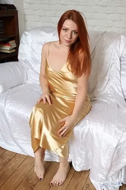 Kate Star at Satin Silk Fun | Redhead Kate Star is barefoot and relaxing on a white satin sheet which is laid over her brown leather sofa. She is wearing a long, soft, shiny, golden satin chemise which looks fabulous on her but we are tempted by more of a tease and she knows it. Is she wearing satin panties, you may just be about to find out