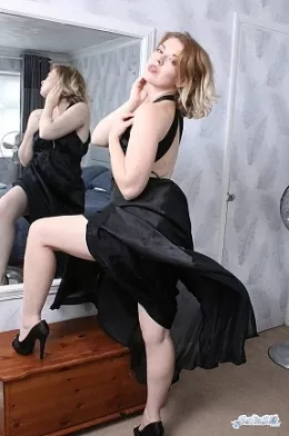 Helen Stephens at Satin Silk Fun | Looking just about ready for a night out we find Helen Stephens wearing a long black satin dress. It's a hot day and the fan is on to cool her down but it really makes the soft shiny fabric of her dress roll around her fine body, caressing it and billowing up to give us all a flash or her satin panties