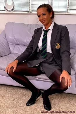 Lara Lee at Gloss Tights Glamour | Behind-the-scenes Video footage from shoot with Lara Lee wearing a college uniform outfit comprising: grey blazer, white shirt & college tie (sans bra), grey pleated skirt, black sheer glossy legwear with white fullback cotton briefs/panties underneath, and black ballet flat footwear that is removed to show off toes/feet, in a glorious tease to naughty nude that provides a closer inspection of her tights/pantyhose, and much more besides!    4K Video download available