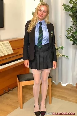 Cassie B at Upskirt Glamour | Behind-the-scenes BTS video footage from shoot with Cassie B wearing a college uniform comprising; Black blazer, pale blue shirt (sans bra), college tie, grey pleated skirt, white stockings & black suspenders, red lace panties, and black high-heeled court shoes that stay on throughout, in a tease to topless.  4K Video download available